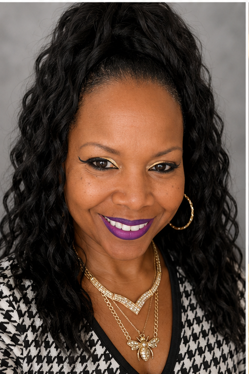 Headshot of a smiling woman wearing hoop earrings, a layered gold necklace with a bee pendant, and purple lipstick.