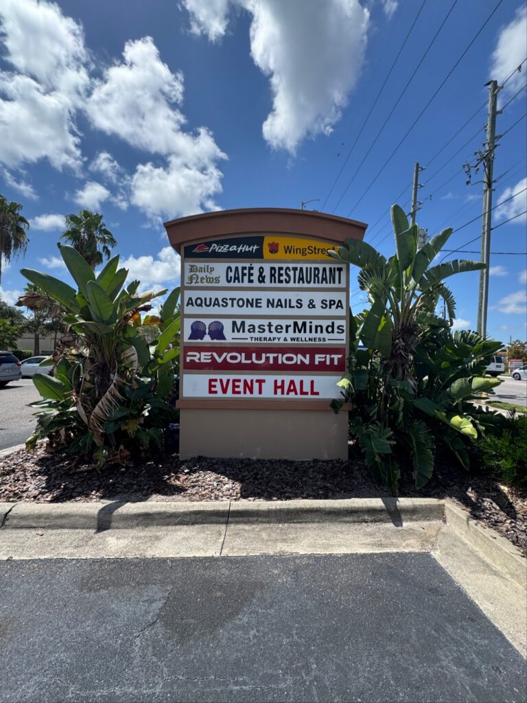 A business directory sign listing Pizza Hut, WingStreet, Daily News Café & Restaurant, Aquastone Nails & Spa, MasterMinds Therapy & Wellness, Revolution Fit, and an Event Hall.