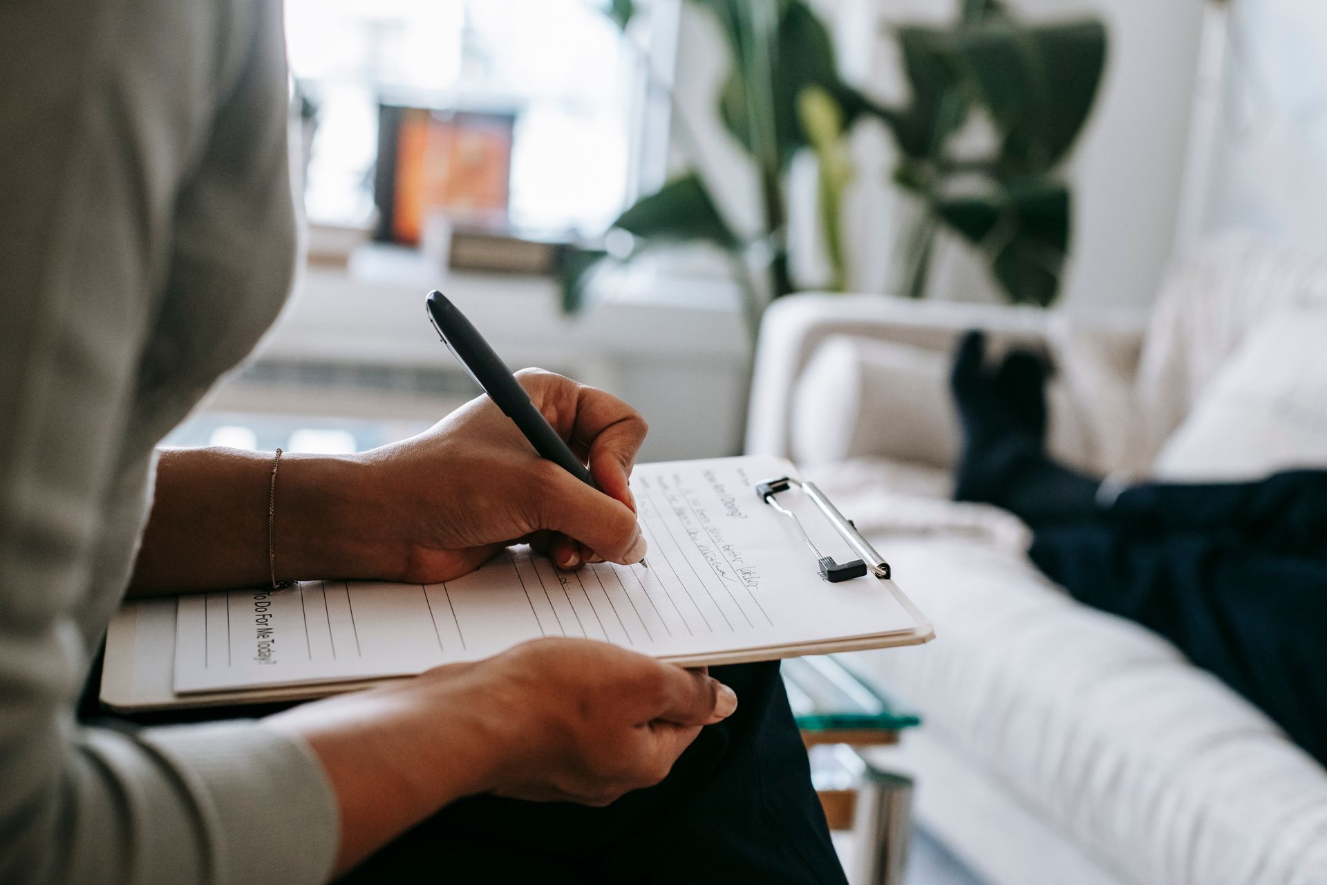 A person holding a pen writes on a clipboard during a therapy session.